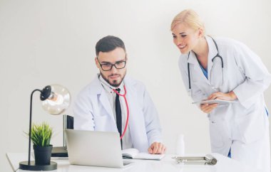 Doktor hastane ofis dizüstü bilgisayar masanın üzerinde başka bir doktor hasta sağlık hakkında tartışma ile çalışma.