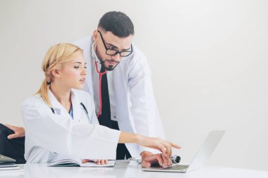 Doktor hastane ofis dizüstü bilgisayar masanın üzerinde başka bir doktor hasta sağlık hakkında tartışma ile çalışma.