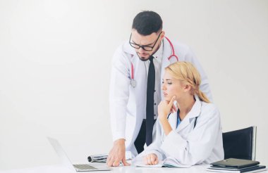 Doktor hastane ofis dizüstü bilgisayar masanın üzerinde başka bir doktor hasta sağlık hakkında tartışma ile çalışma.