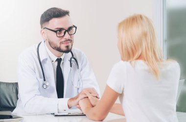Erkek doktor hastane ofiste bayan hasta hasta ellerini tutarak yatıştırır. Sağlık ve tıbbi hizmet.