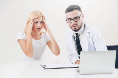 Erkek doktor hastane ofiste bayan hasta masada dizüstü bilgisayarda hastalar sağlık verilere bakarken konuştuğu. Sağlık ve tıbbi hizmet.