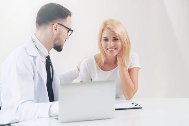 Erkek doktor hastane ofiste bayan hasta masada dizüstü bilgisayarda hastalar sağlık verilere bakarken konuştuğu. Sağlık ve tıbbi hizmet.