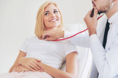 Erkek doktor konuşuyor ve Bayan hasta hastane ofisinde inceleyerek. Sağlık ve tıbbi hizmet.