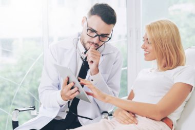 Erkek doktor ve Bayan hasta sağlık veri kaydı için tablet bilgisayar bakıyor. Sağlık ve tıbbi hizmet.