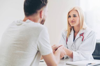 Kadın doktor hastane office odasında erkek hasta ile karşılıklı yapıyor. Sağlık ve Medikal hizmet meslekleri.