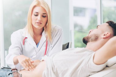 Kadın doktor konuşuyor ve erkek hasta hastane ofisinde inceleyerek. Sağlık ve tıbbi hizmet.