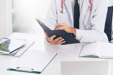 Doktor ofisinde hastanede bir kitap üzerine not yazarken okuma. Tıbbi ve sağlık kavramı.