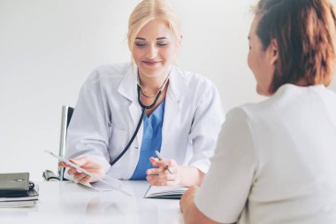 Kadın doktor konuşuyor ve Bayan hasta hastane ofisinde inceleyerek. Sağlık ve tıbbi hizmet.