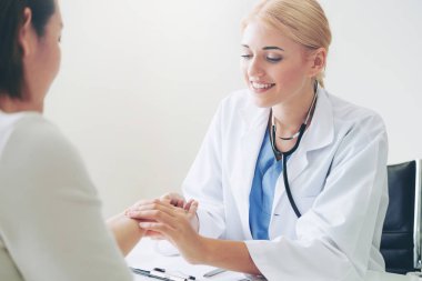 Kadın doktor hastane ofiste bayan hasta için eller tarafından hasta darbe incelenirken konuşuyor. Sağlık ve tıbbi hizmet.
