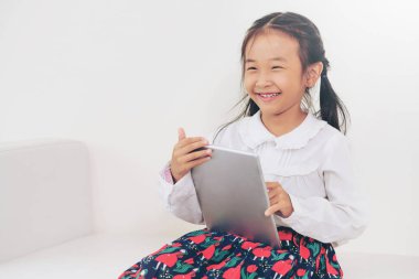 Tablet bilgisayar ile beyaz arka plan üzerinde küçük mutlu çocuk. Çocukluk yaşam tarzı.