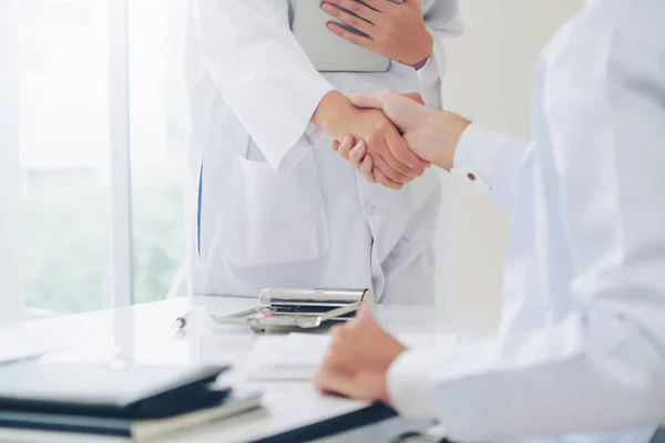 成功と医療スタッフのチームワークを示す別の医者に握手を与える病院医師 — ストック写真