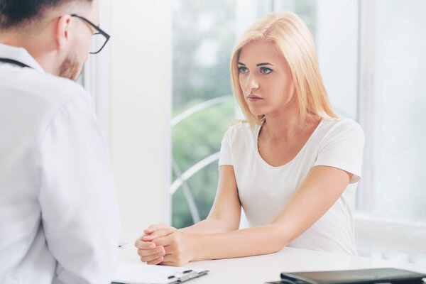 Male doctor is talking to female patient in hospital office. Healthcare and medical service.