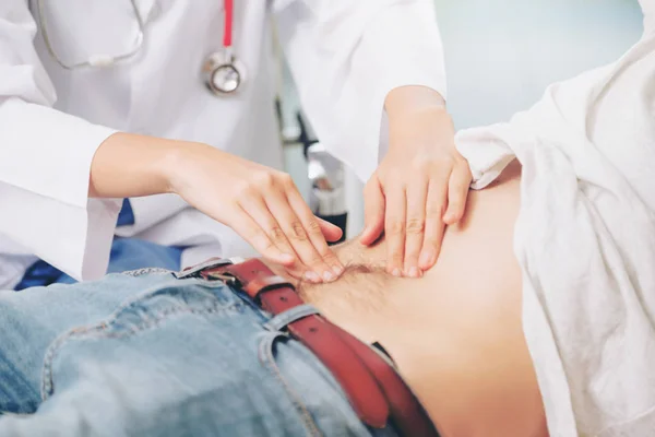 Woman doctor is talking and examining male patient in hospital office. Healthcare and medical service.