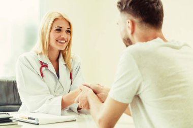 Kadın doktor hastane office odasında erkek hasta ile karşılıklı yapıyor. Sağlık ve Medikal hizmet meslekleri.