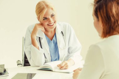 Kadın doktor konuşuyor ve Bayan hasta hastane ofisinde inceleyerek. Sağlık ve tıbbi hizmet.