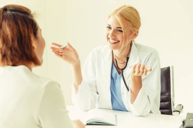 Kadın doktor konuşuyor ve Bayan hasta hastane ofisinde inceleyerek. Sağlık ve tıbbi hizmet.