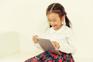 Tablet bilgisayar ile beyaz arka plan üzerinde küçük mutlu çocuk. Çocukluk yaşam tarzı.