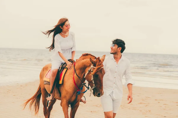 年轻夫妇去蜜月骑马在海滩上的夏天假期 — 图库照片
