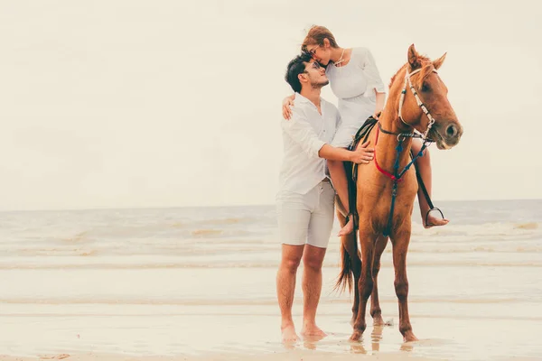 若いカップルがビーチで夏休みに新婚旅行乗馬 — ストック写真