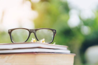 Yumuşak odak retro tarzı kitap ve göz gözlük doğa arka plan ile. Okuma ve eğitim kavramı.