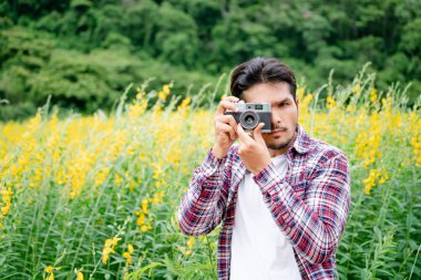Genç hipster adam alarak fotoğraf ile eski stil fotoğraf makinesi doğa manzara arka plan ile. Retro ve vintage fotoğraf kavramı.