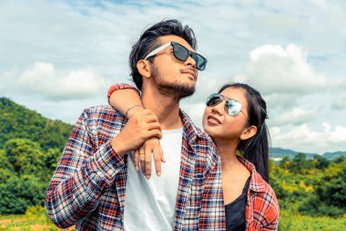 Mutlu çift tepelerde yeşil çim alandaki romantik bir yürüyüşe çık. Seyahat ve balayı konsepti.