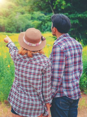 Mutlu çift tepelerde yeşil çim alandaki romantik bir yürüyüşe çık. Seyahat ve balayı konsepti.