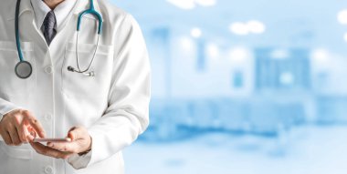 Hastanede cep telefonu kullanan bir erkek doktor. Sağlık ve doktor hizmetleri.