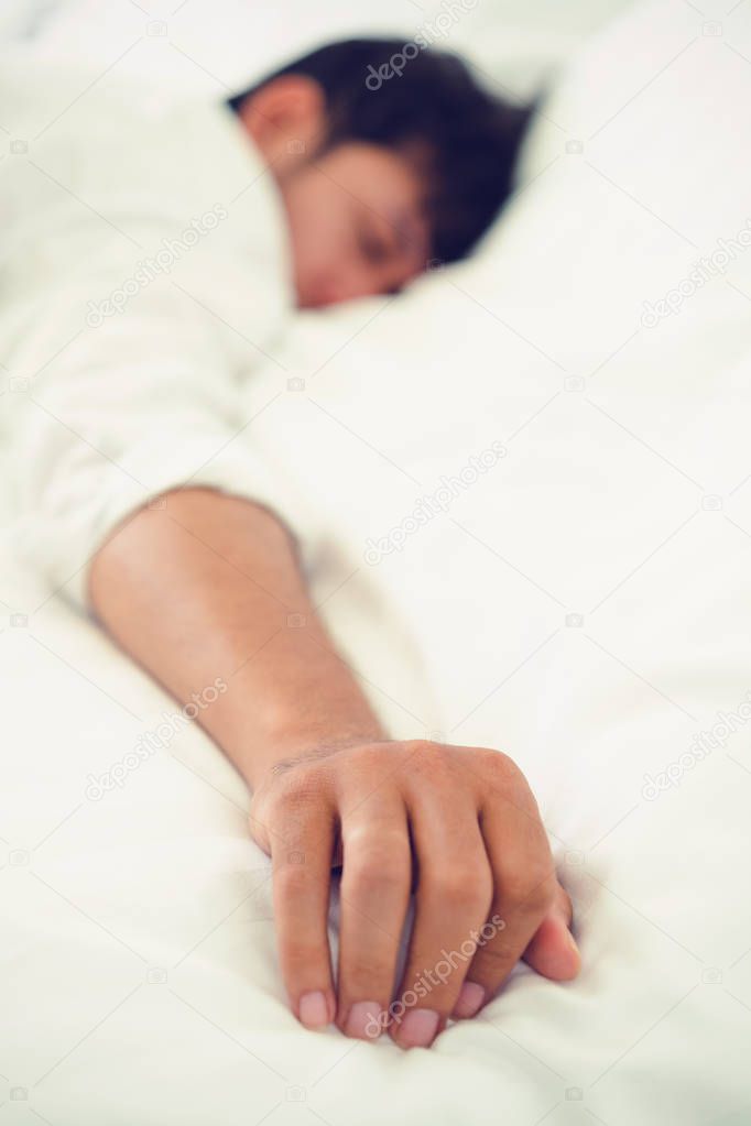 Young man sleep in white linen bed in the bedroom.