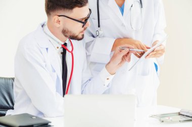 Doktor hastane ofis dizüstü bilgisayar masanın üzerinde başka bir doktor hasta sağlık hakkında tartışma ile çalışma.