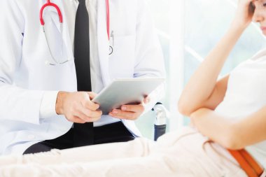 Erkek doktor konuşuyor ve Bayan hasta hastane ofisinde inceleyerek. Sağlık ve tıbbi hizmet.