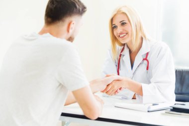 Kadın doktor hastane office odasında erkek hasta ile karşılıklı yapıyor. Sağlık ve Medikal hizmet meslekleri.