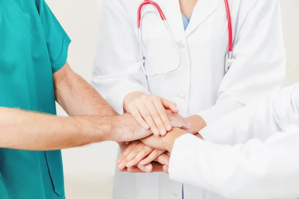 Medical service teamwork - Doctor, surgeon and nurse join hands together.