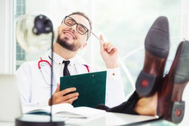 Kolay rahat Doktor hastanede ofis masasında mutlu hissediyorum. Tıbbi ve sağlık kavramı.