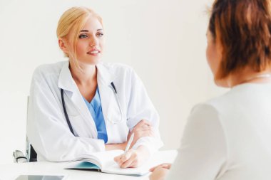 Kadın doktor konuşuyor ve Bayan hasta hastane ofisinde inceleyerek. Sağlık ve tıbbi hizmet.