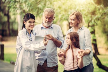 Mutlu sağlıklı aile ve parkta konuşan doktor. İnsanların sağlık ve tıbbi personel hizmet anlayışı.