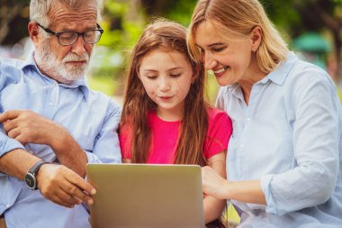 Mutlu aile dizüstü bilgisayar birlikte bahçe parkta yaz aylarında kullanma.. Çocuk eğitim ve aile etkinlikleri kavramı.