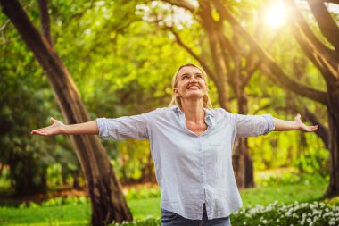 Parkta dans mutlu orta yaşlı kadın portresi. Kadın mutlulukla gülümsüyor. Emeklilik kavramı.