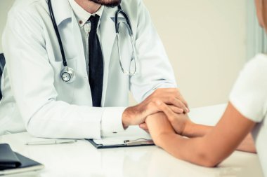 Erkek doktor hastane ofiste bayan hasta hasta ellerini tutarak yatıştırır. Sağlık ve tıbbi hizmet.
