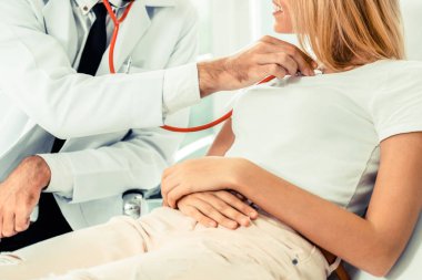 Erkek doktor konuşuyor ve Bayan hasta hastane ofisinde inceleyerek. Sağlık ve tıbbi hizmet.