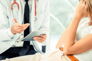 Erkek doktor konuşuyor ve Bayan hasta hastane ofisinde inceleyerek. Sağlık ve tıbbi hizmet.