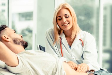 Kadın doktor konuşuyor ve erkek hasta hastane ofisinde inceleyerek. Sağlık ve tıbbi hizmet.