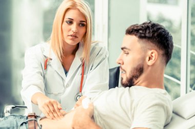 Kadın doktor konuşuyor ve erkek hasta hastane ofisinde inceleyerek. Sağlık ve tıbbi hizmet.