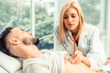 Kadın doktor konuşuyor ve erkek hasta hastane ofisinde inceleyerek. Sağlık ve tıbbi hizmet.