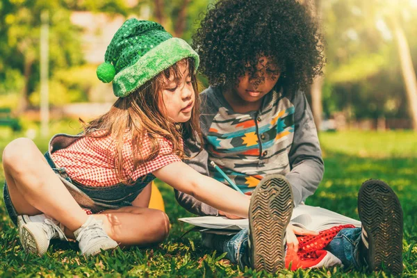 学校的男孩和女孩一起在公园里看书 教育和朋友理念 — 图库照片