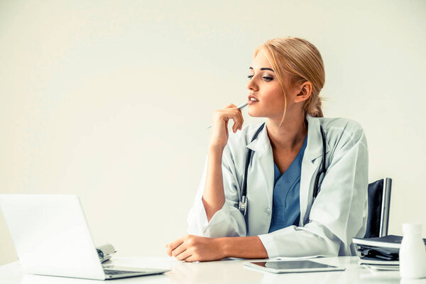 Woman doctor in hospital or healthcare institute working on medical report at office table.