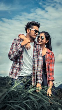 Mutlu çift tepelerde yeşil çim alandaki romantik bir yürüyüşe çık. Seyahat ve balayı konsepti.