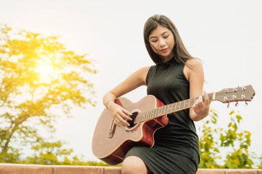 Mutlu kadın doğa arka plan ile gitar çalıyor. Müzik ve gevşeme kavramı.