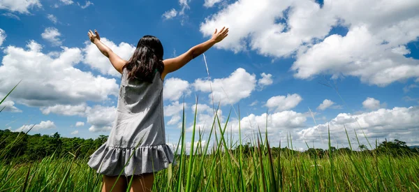 夏の日の晴れた青空に腕を広める緑の草の牧草地に若い美しい女性 逃走と瞑想の概念 — ストック写真