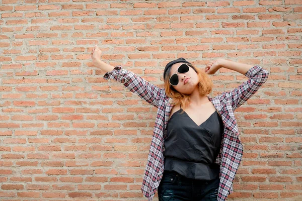 Tuğla duvar şehirdeki sokak karşı duran mutlu genç hipster kadın.
